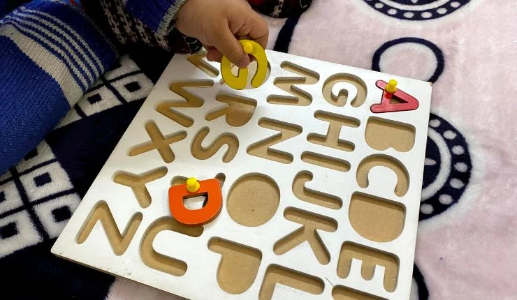 anak bermain puzzle huruf